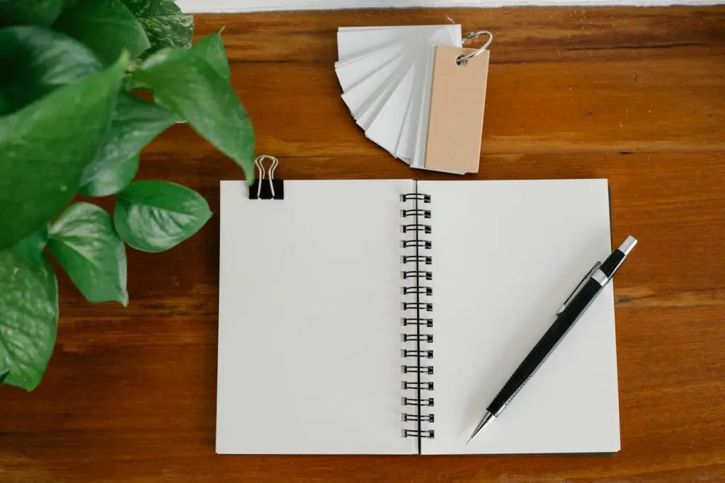 Aufgeschlagenes Notizbuch mit Stift auf einem Holztisch – Symbolbild